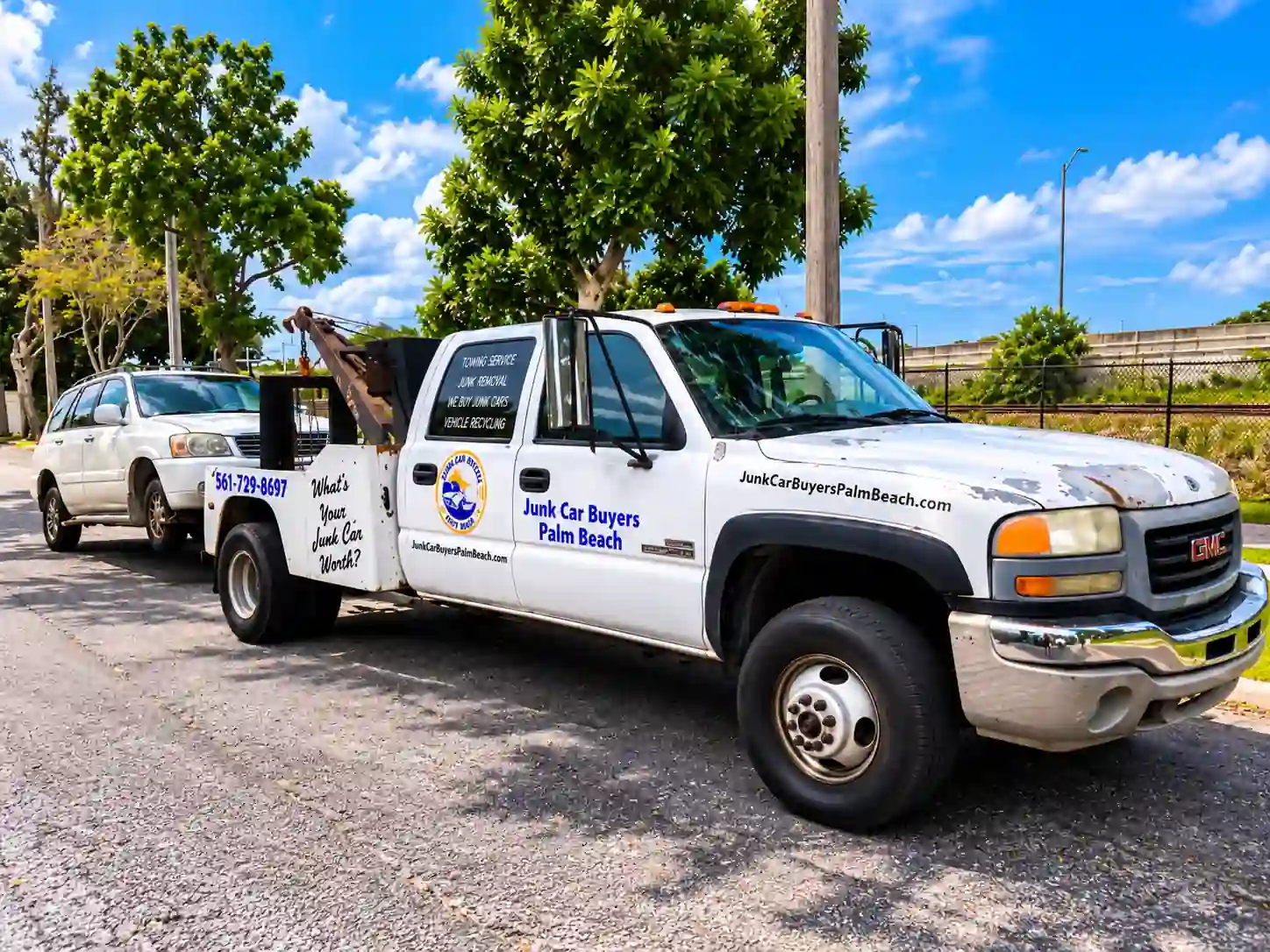 A Junk Car Buyers Palm Beach tow truck towing a silver SUV